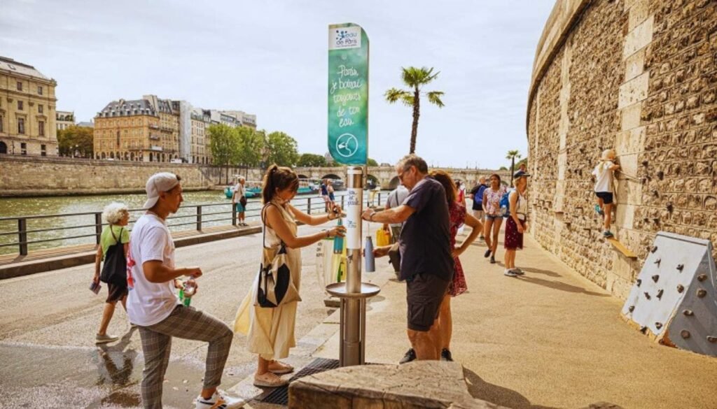 A bustling street scene in a charming European city, showcasing various water-saving tips and tricks. In the foreground, a variety of small, everyday household items are displayed, such as water bottles, faucet attachments, and rain collection devices. The middle ground features pedestrians strolling past quaint storefronts and cafes, some carrying reusable water containers. In the background, the city's historic architecture and lush greenery create a picturesque backdrop, conveying a sense of tranquility and sustainability. The lighting is soft and natural, casting warm, golden hues across the scene. The overall mood is one of practicality, efficiency, and environmental awareness. Usar Bebedouros Públicos em Paris é uma das formas de economizar