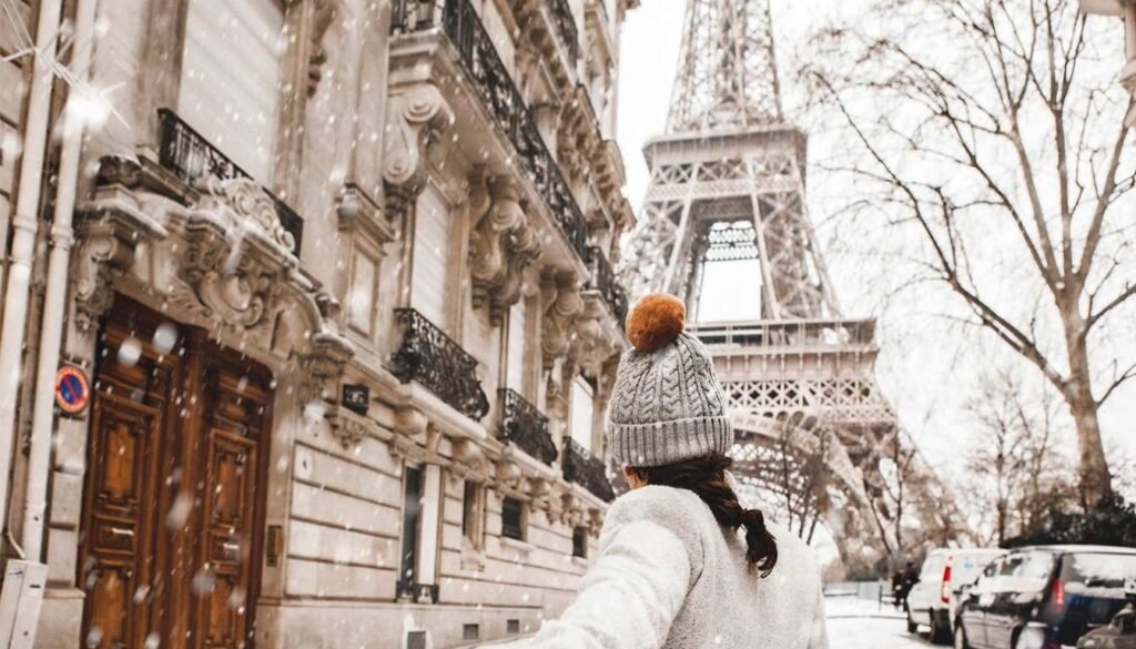 A chilly winter day in Paris, the Eiffel Tower standing tall against an overcast sky. The city's iconic landmarks are shrouded in a soft, misty veil, lending an air of quiet contemplation. In the foreground, a lone pedestrian strolls along the banks of the Seine, their scarf billowing gently in the breeze. The trees lining the riverfront are bare, their branches casting delicate shadows across the cobblestone streets. The muted color palette of grays and blues evokes a sense of calm and tranquility, inviting the viewer to experience the city's enchantments during the low season. A Torre Eiffel no Inverno Rigoroso