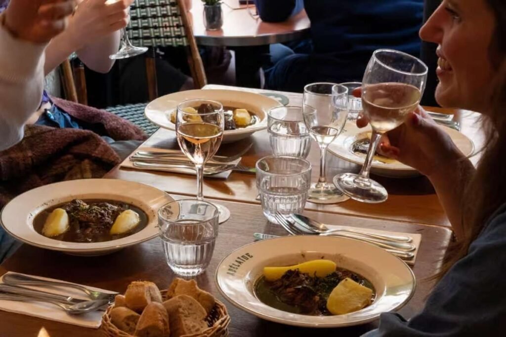 A sumptuous display of traditional French savory dishes, captured in a warm, inviting setting. In the foreground, a selection of flaky, golden-brown croissants and buttery pain au chocolat, fresh from the oven. The middle ground features an array of savory crepes, sizzling on a cast-iron griddle, their delicate fillings oozing with cheese and herbs. In the background, a table laden with hearty croque monsieurs, their crisp, golden exteriors revealing a melted, gooey interior. Soft, diffused lighting casts a cozy, atmospheric glow, while the rustic, wooden accents and muted color palette evoke the charming ambiance of a Parisian cafe. The scene exudes the comforting, indulgent flavors that define the beloved savory specialties of French cuisine. Pratos salgados da Culinária Francesa em Paris