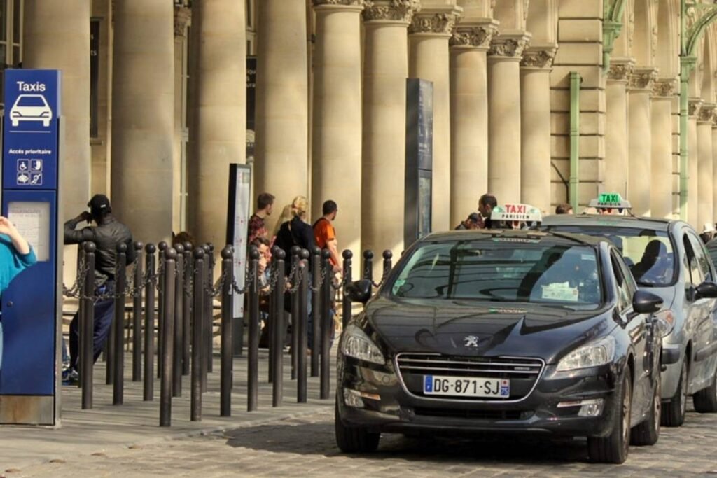 A bustling urban scene in Paris, France, captured through a wide-angle lens. In the foreground, a variety of transportation modes are visible, including classic Parisian taxis, sleek metro trains, and the iconic double-decker buses. The middle ground features pedestrians navigating the lively streets, while in the background, the iconic Eiffel Tower and other Parisian landmarks stand tall, bathed in a warm, golden-hour glow. The overall atmosphere conveys the vibrant, cosmopolitan energy of the City of Light, with a focus on the diverse range of transportation options available to visitors and locals alike. Como se locomover aos Pontos Turísticos de Paris