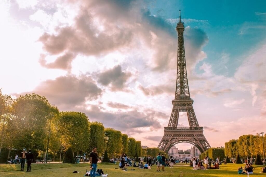 A majestic, iconic tower standing tall against a vibrant sky, the Eiffel Tower in Paris, France. Towering over the city, its intricate latticed steel frame and elegant arched design capturing the essence of French engineering and architecture. The foreground features the tower's grand silhouette, with its distinctive shape and intricate details. The middle ground showcases the surrounding Parisian cityscape, with its historic buildings, bustling streets, and lush greenery. The background depicts a warm, golden-hued sunset, casting a soft, romantic glow over the entire scene. The overall composition conveys a sense of grandeur, timelessness, and the quintessential Parisian experience.