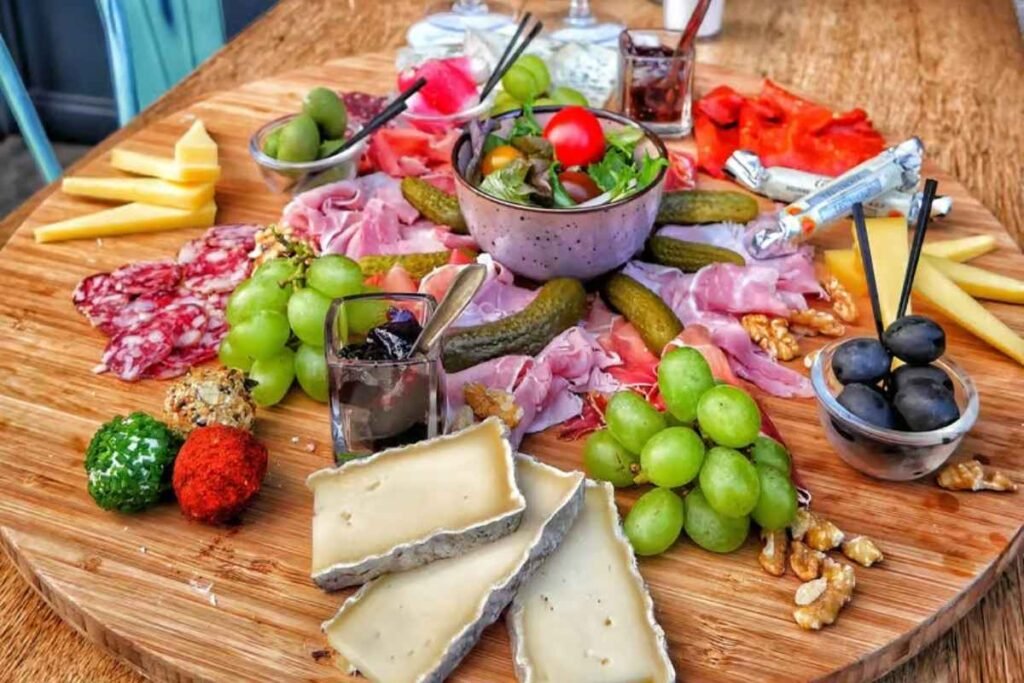 A vibrant still life depicting a platter of artisanal queijos, the pride of Parisian cuisine, captured in warm, golden hues. The foreground features an assortment of creamy, pungent cheeses, their textures and colors accentuated by dramatic lighting. In the middle ground, a scattering of crusty bread, fresh grapes, and a small bowl of honey, inviting the viewer to savor the flavors of this quintessential Parisian delight. The background is softly blurred, evoking the intimate, convivial atmosphere of a Parisian café, where locals and visitors alike indulge in the city's culinary delights. tábua de frios em paris, com variedade de queijos, embutitos, frutas, pastas, nozes e doces